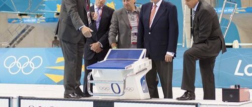 Глава хронометражной службы Omega Петер Хюрцелер (Peter Hürzeler), слева, объясняет принцип работы хронометражной системы для соревнований по плаванию председателю оргкомитета Олимпиады в Лондоне Себастьяну Коу (Sebastian Coe), главе Swatch Group Нику Хайеку (Nick Hayek), президенту МОК Жаку Рогге (Jacques Rogge) и президенту Omega Стивену Уркхарту (Stephen Urquhart) в Олимпийском парке в Лондоне